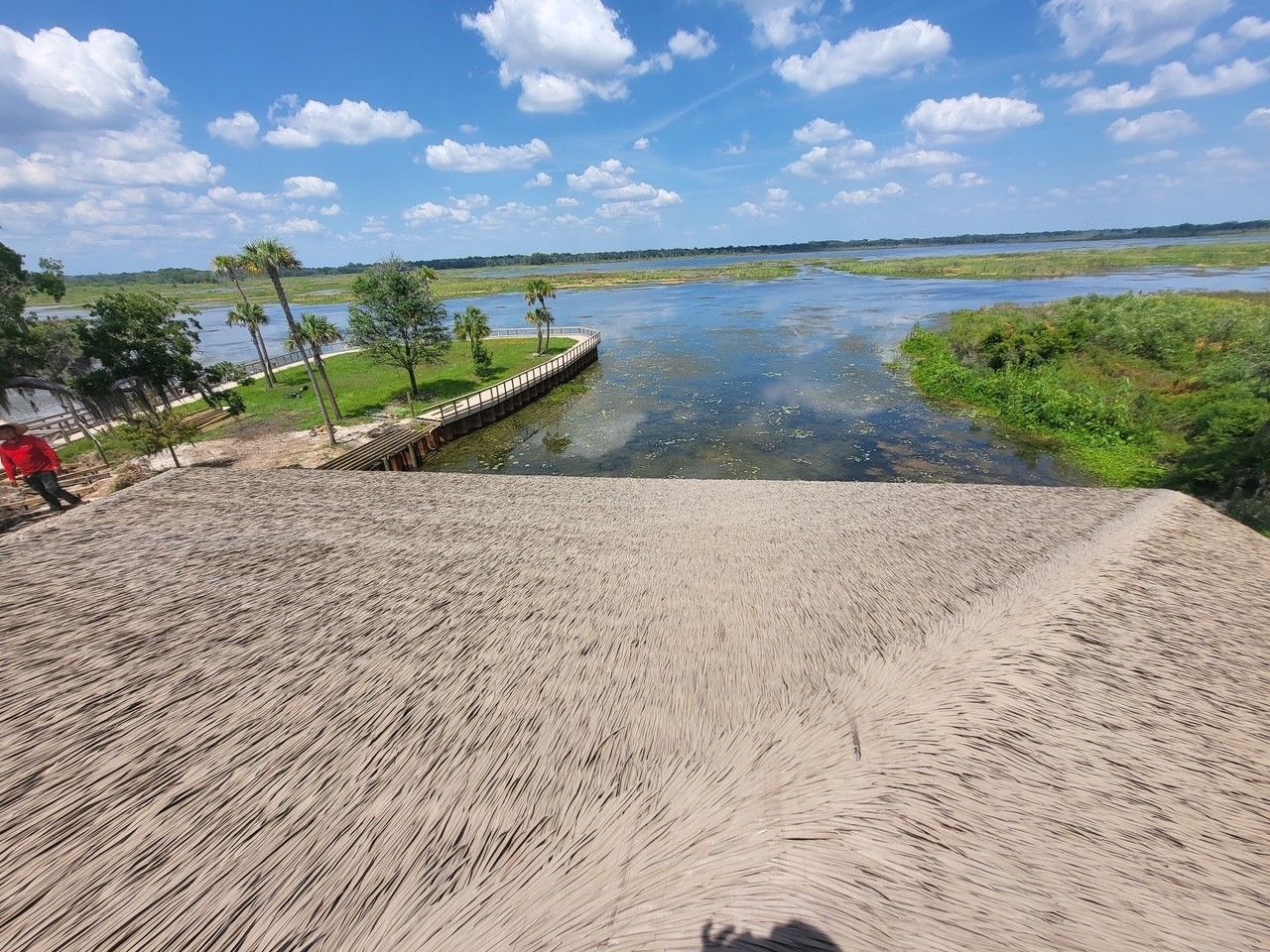 Sandy boat ramp leading to a calm lake with grassy shore and blue sky with clouds