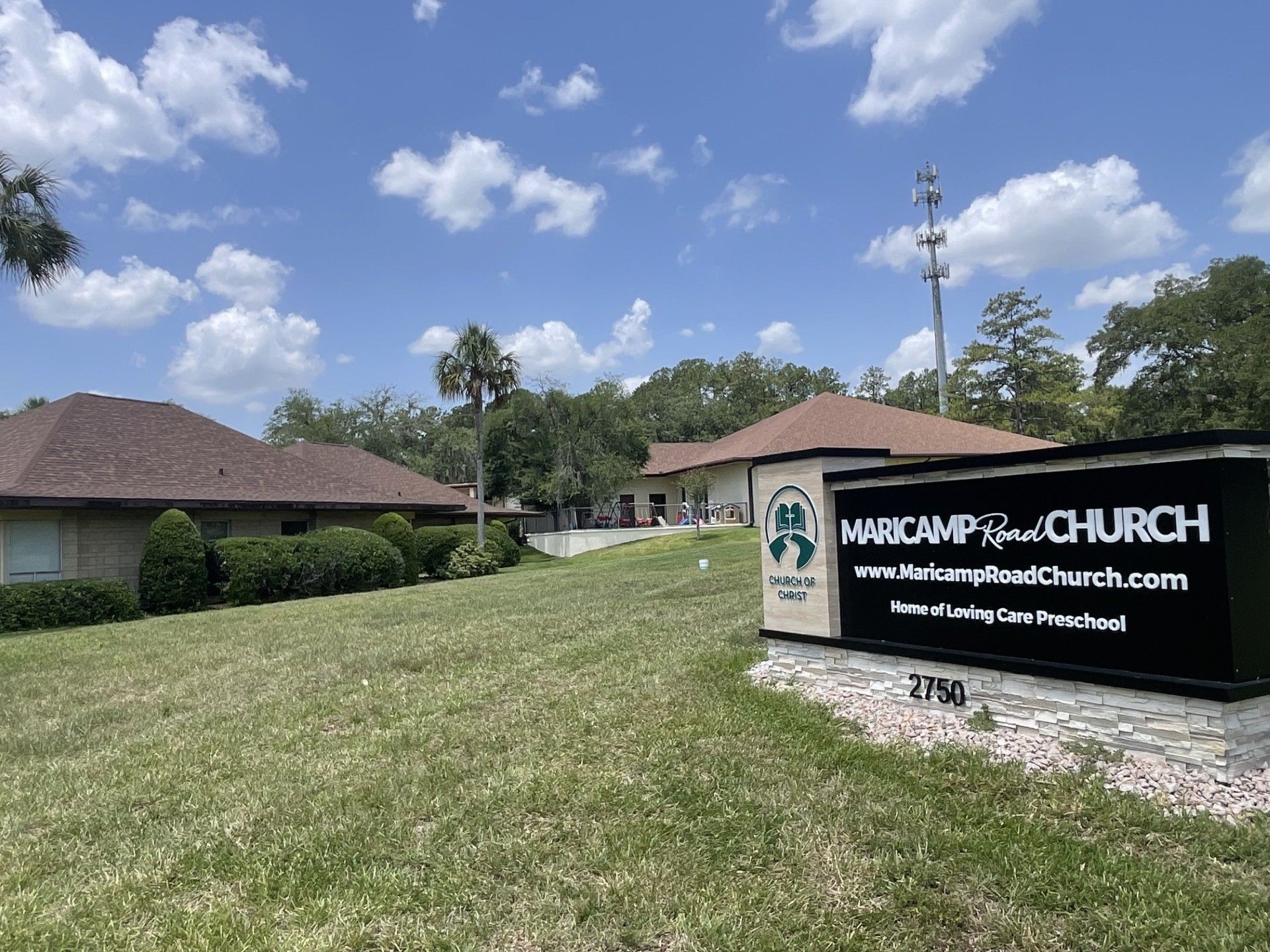 Church campus with sign in front of low buildings and a partly cloudy sky
