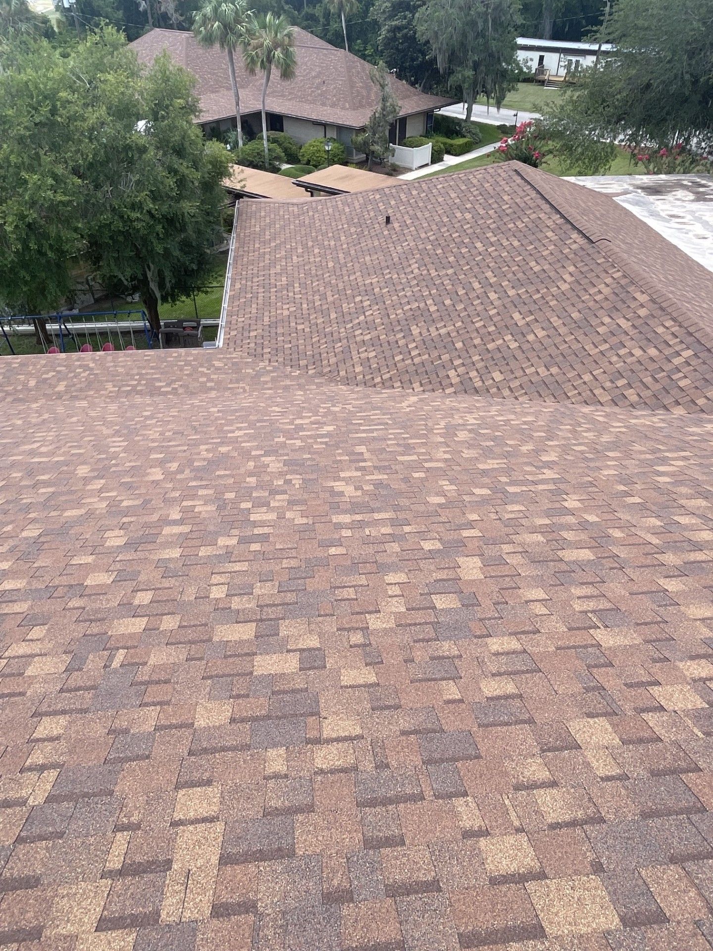 Rooftops with brown shingles and trees in a residential neighborhood view