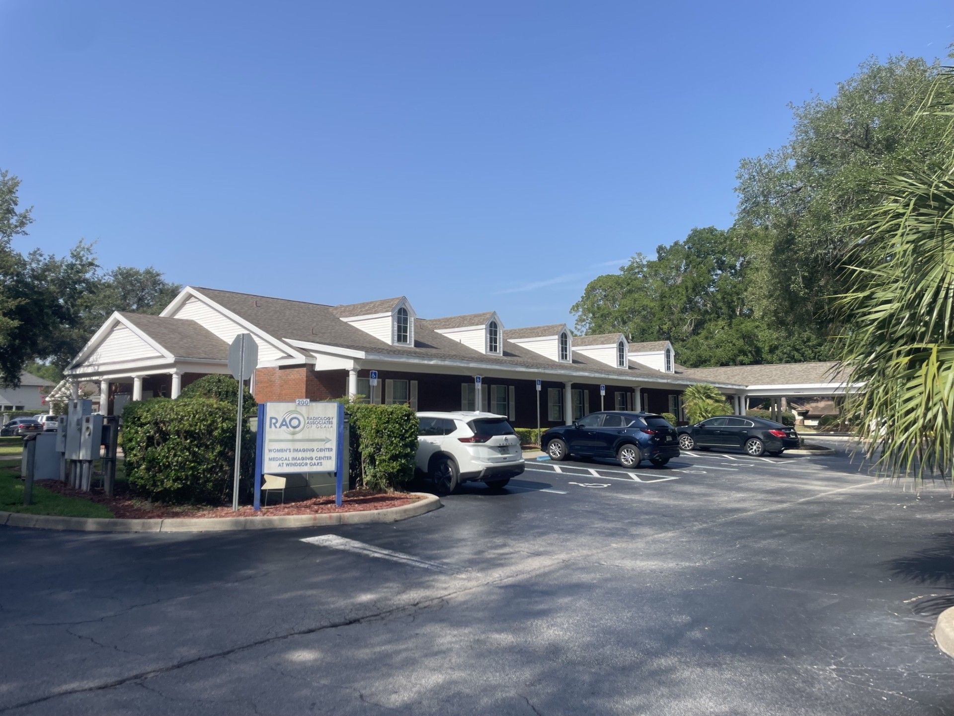 Motel-style building with parked cars and a sign under a clear blue sky