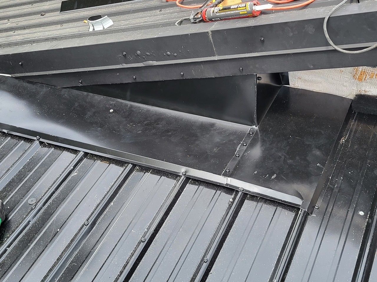 Black metal trailer bed with a sloped ramp and scattered debris underneath.