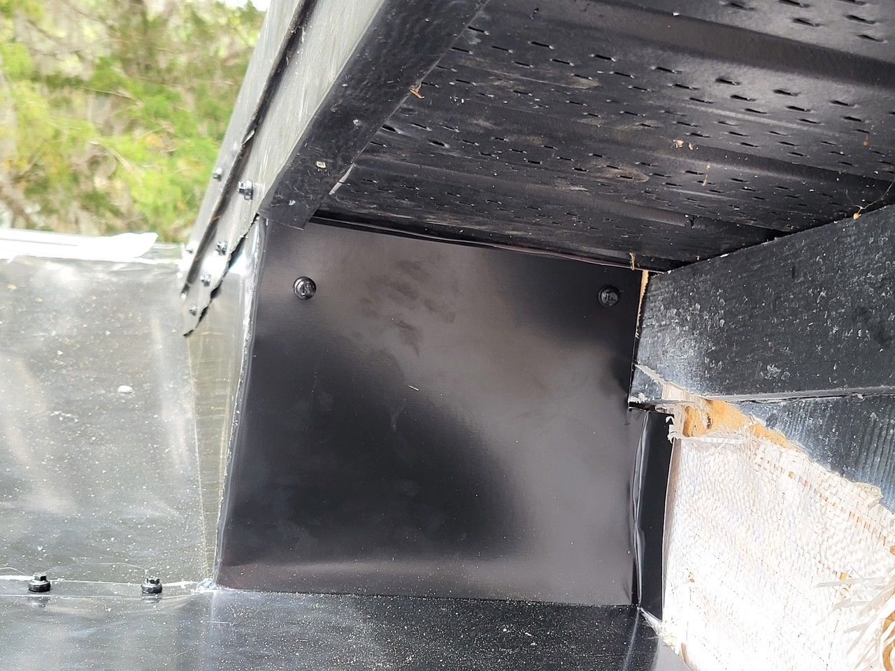 Close-up of a black metal roof edge and gutter flashing on a building exterior