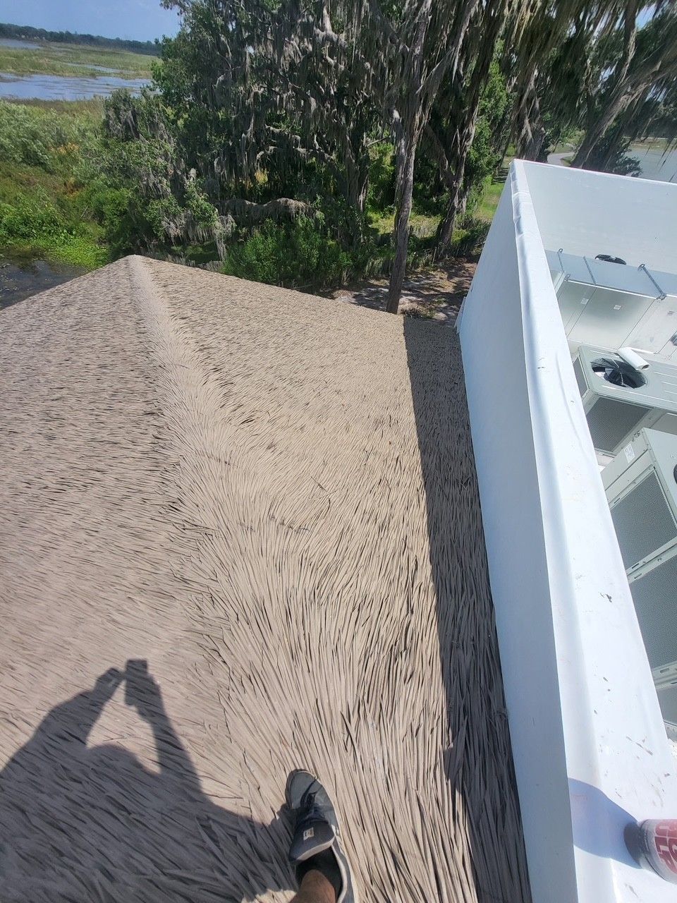 Gravel rooftop beside a white building, with trees and water in the background.