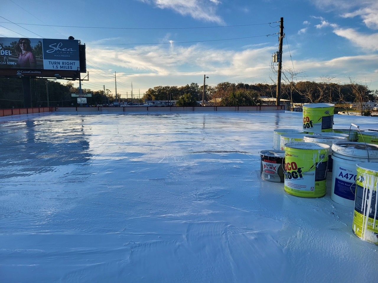 Outdoor ice rink with stacked paint buckets on the ice under a blue sky