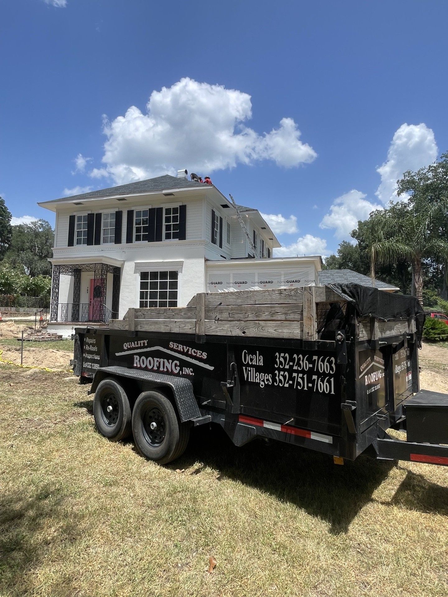 Truck parked in front of a partially renovated white two-story house under a blue sky