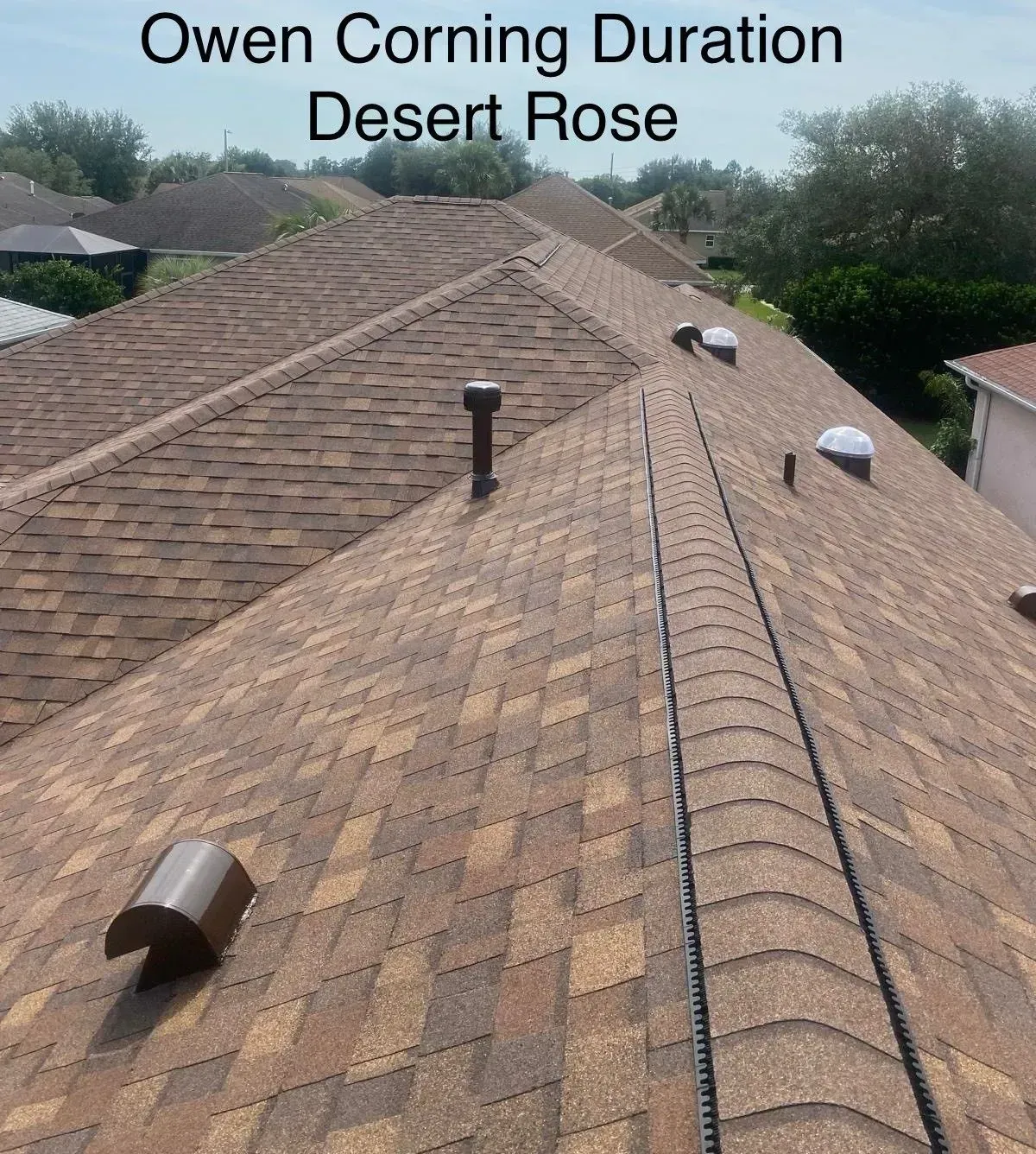 Brown shingle roof with ridge vent and roof vents, labeled “Owen Corning Duration Desert Rose.”
