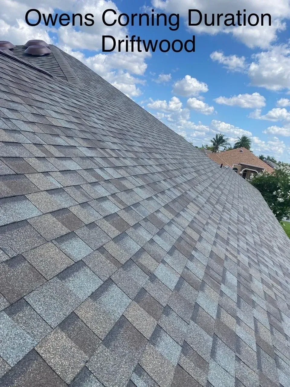 Close-up of a gray Owens Corning Duration Driftwood shingled roof with a cloudy sky.