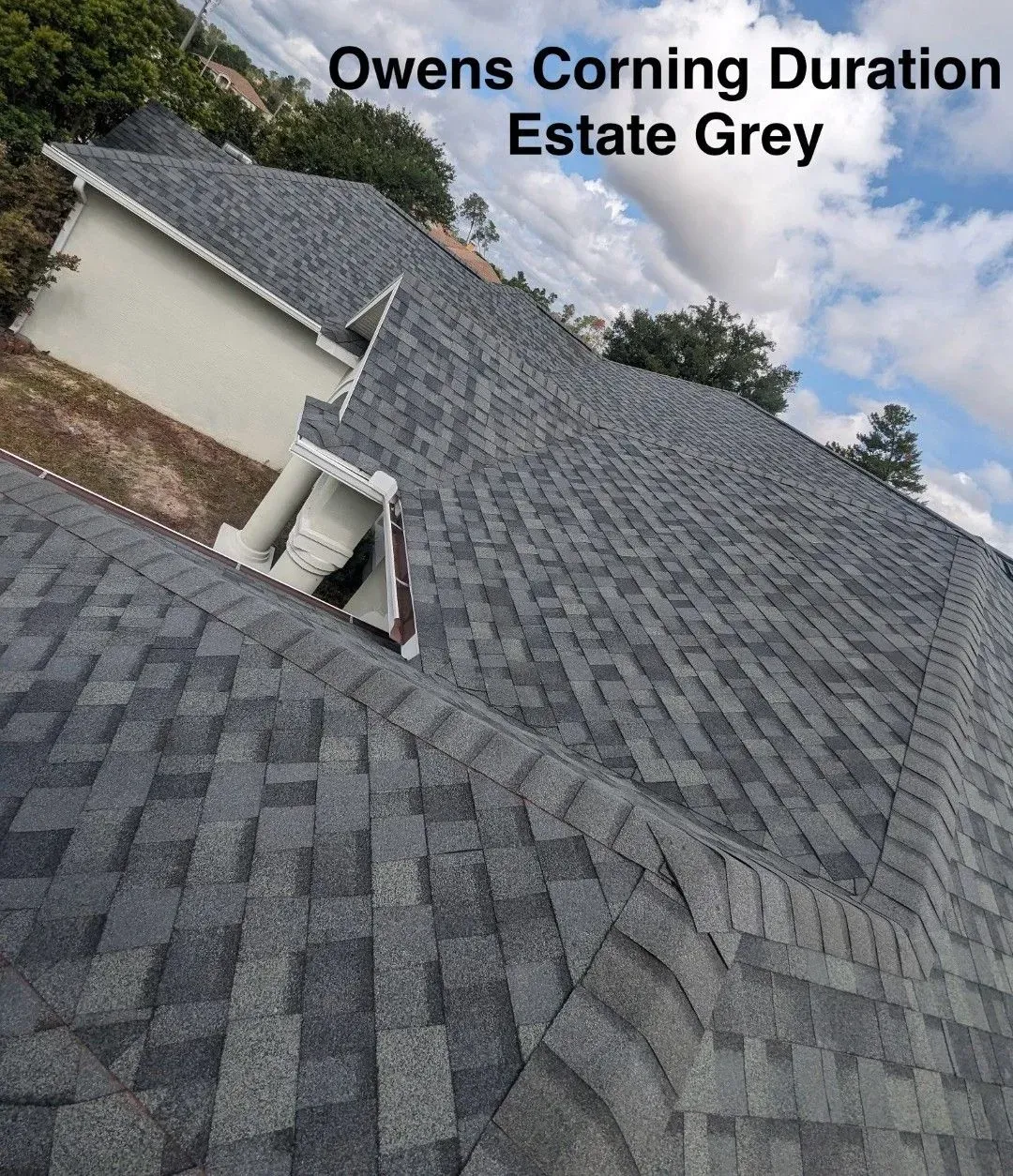 Grey shingle roof on a house under a cloudy sky, labeled 
