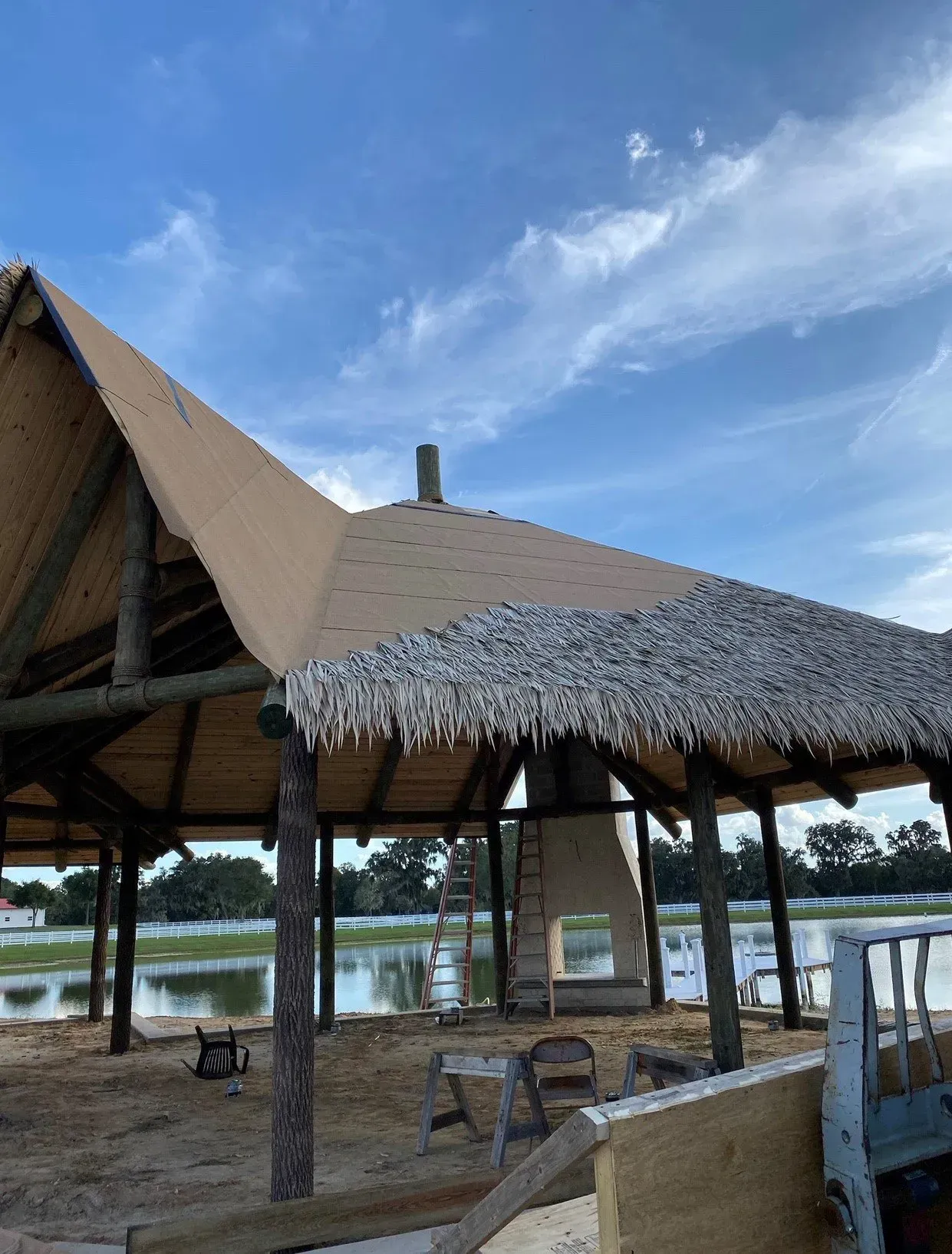 Thatched beach pavilion by a lake under a blue sky