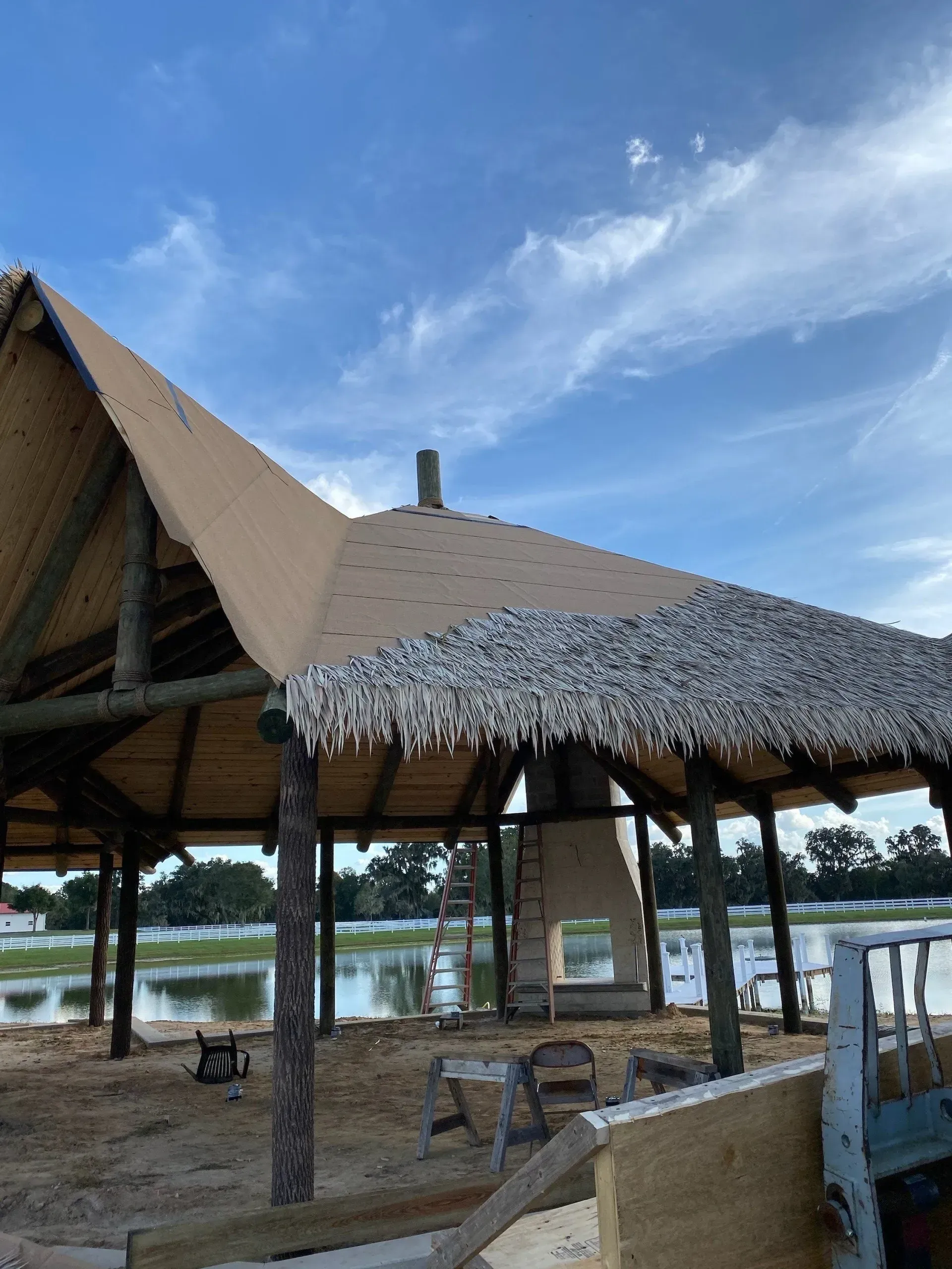 Thatched riverside pavilion with open seating under a blue sky