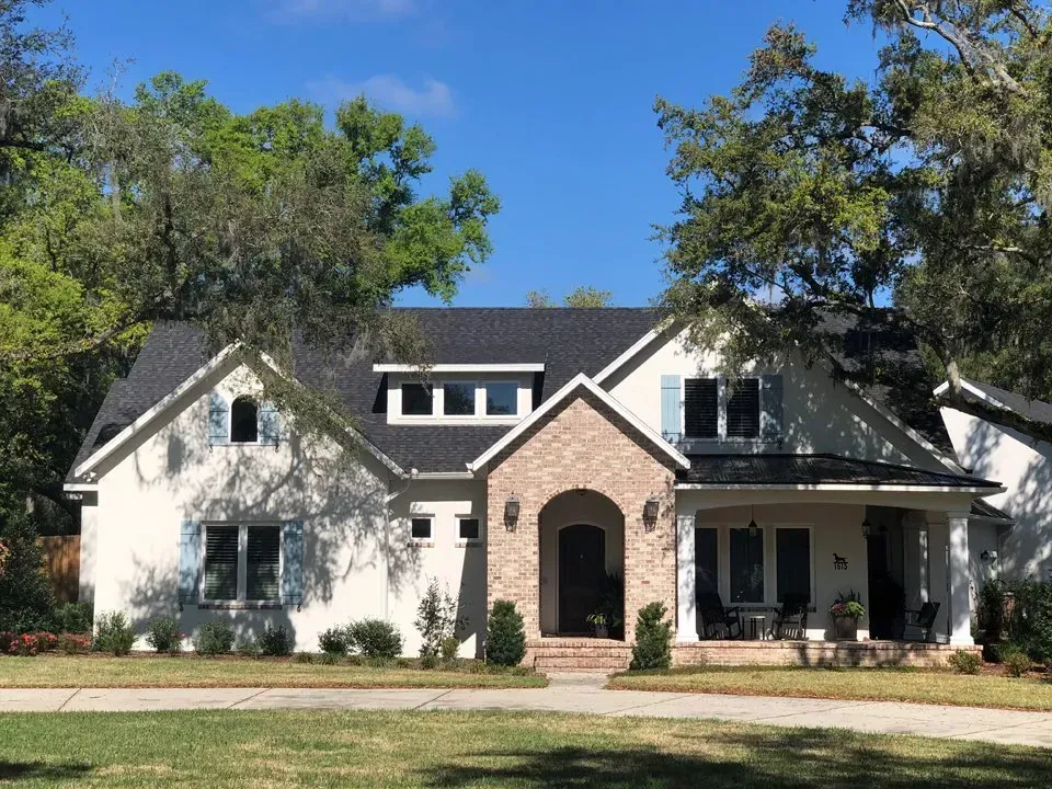 Two-story suburban house with white siding, brick entry, and a front porch under a blue sky