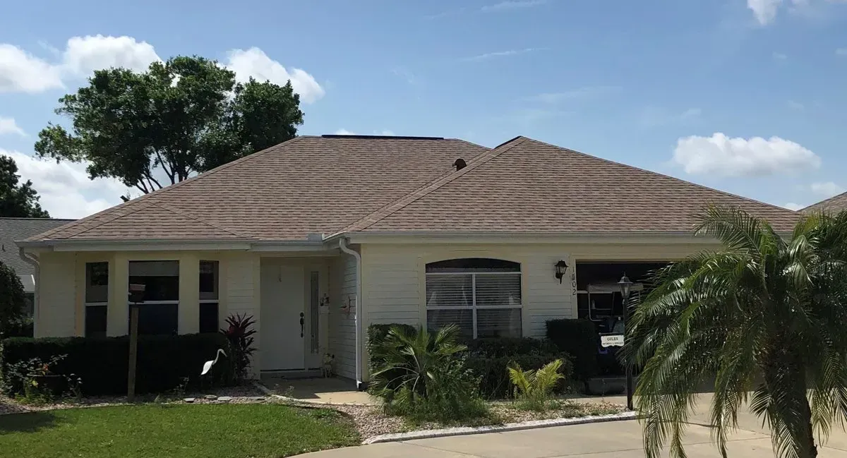 Single-story suburban house with a tiled roof, front porch, and palm tree in the yard.