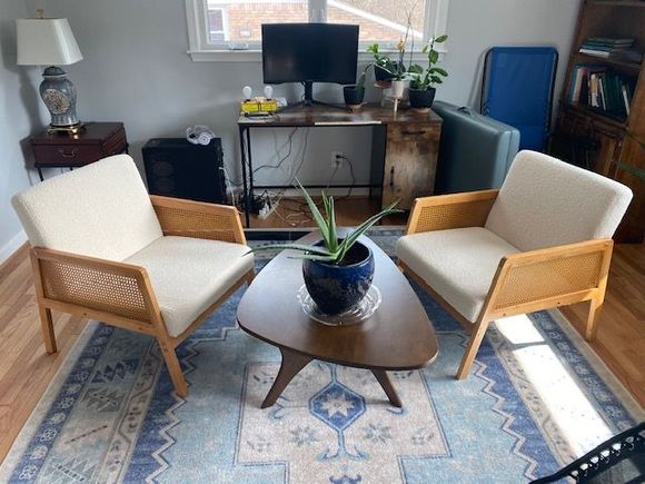 Reception area with gray walls, wooden floor, rug, and desk. A chair sits on the left.