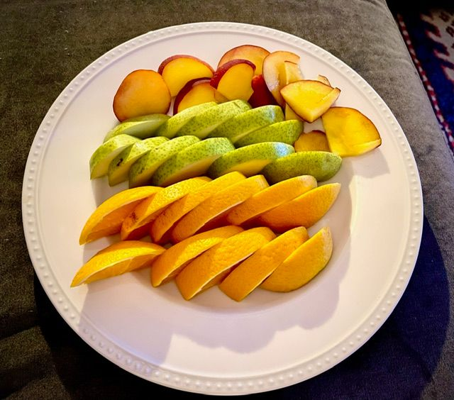 Plate of sliced fruit: oranges, pears, and peaches arranged in rows.