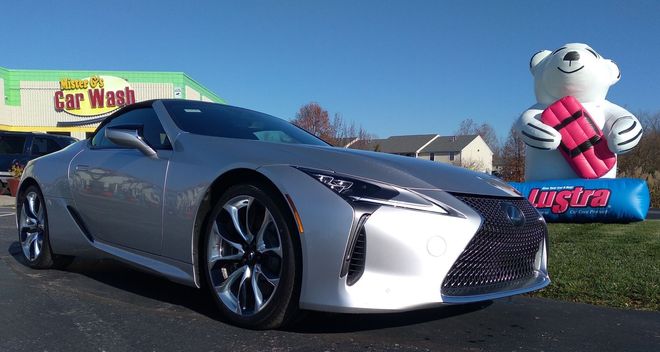 Silver sports car at a car wash, with a polar bear statue in the background.