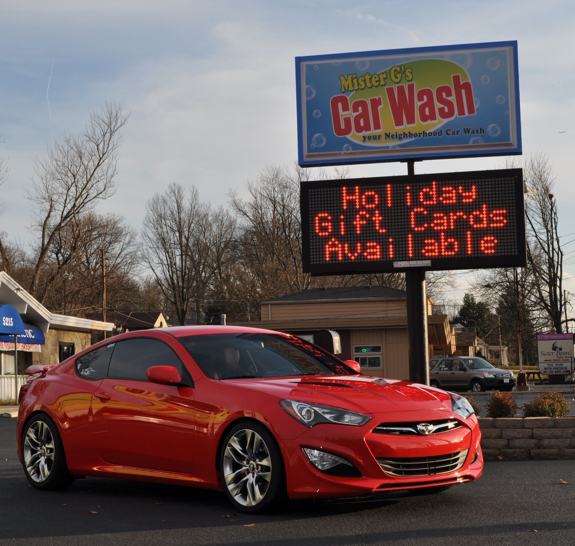 A bright red Hyundai Genesis coupe parked in front of a 