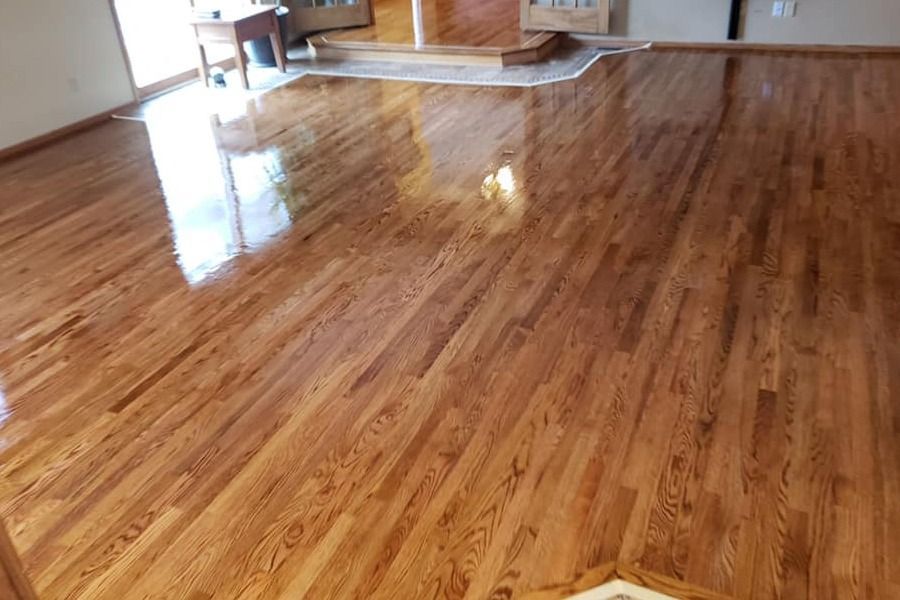 Glossy hardwood floor in a mostly empty room with sunlight reflections.