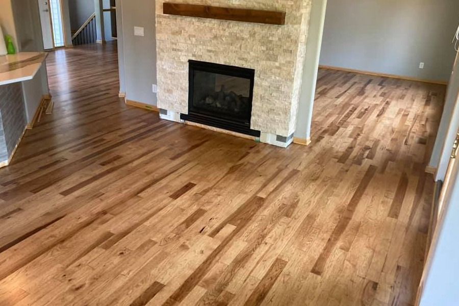 Empty living room with hardwood floors and a stone fireplace
