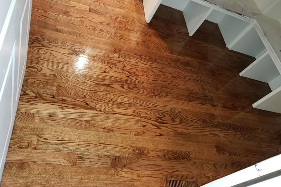 Wooden staircase landing with polished hardwood floors and white railings.