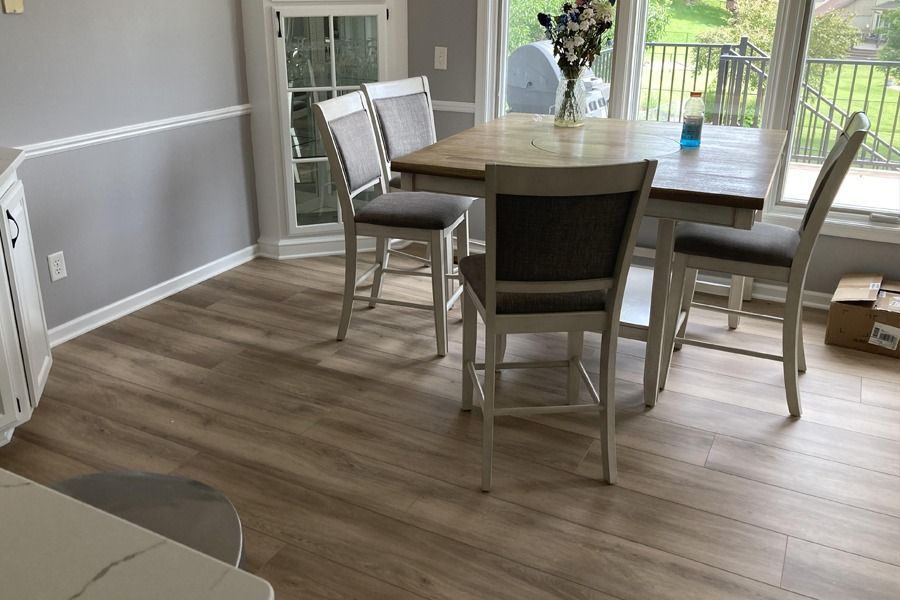 Dining area with a wooden table and chairs on light wood flooring, near sliding glass doors to a deck.