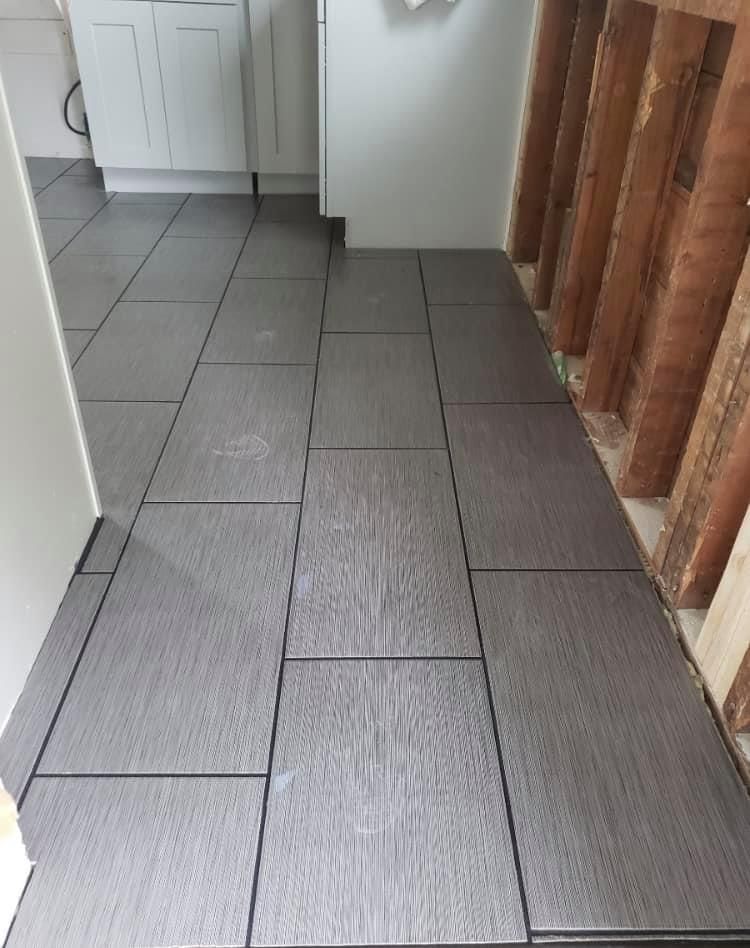 Narrow hallway with gray tiled floor and exposed wooden wall studs on the right