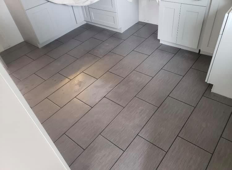Kitchen with gray tile floor and white cabinets along the walls
