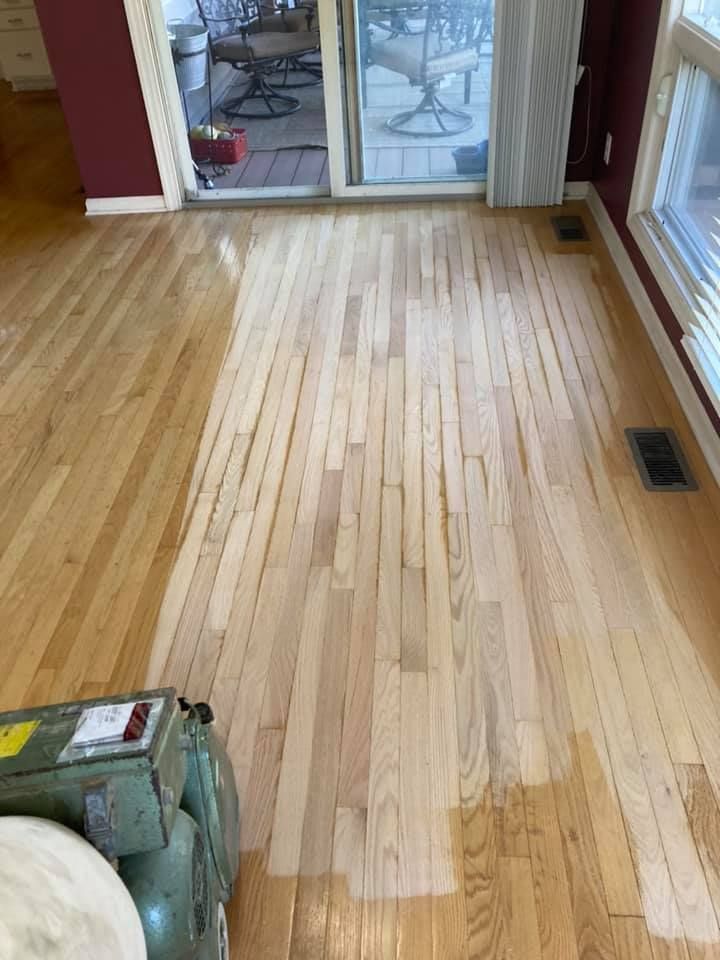 Wooden floor being refinished in a room with red walls and glass doors.