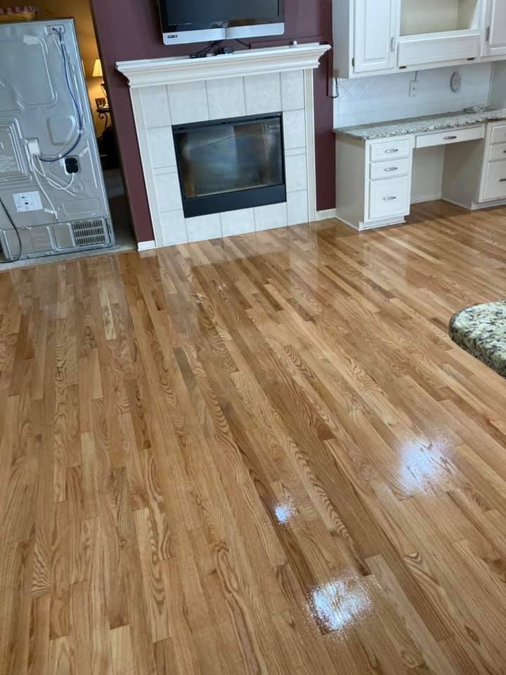 Glossy hardwood living room floor with a fireplace and white desk cabinets along the wall.