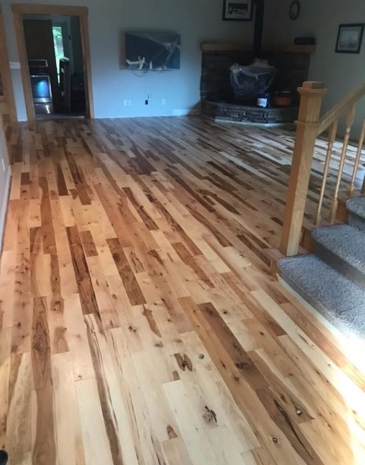 Spacious living room with glossy hardwood floor, carpeted stairs, and a fireplace in the background