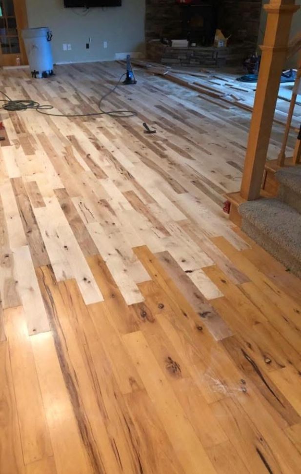 Partially installed hardwood floor in a room, with tools and materials scattered around the edges.