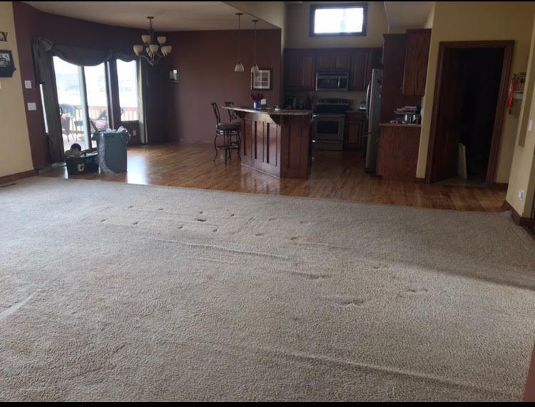 Empty carpeted living room with kitchen and dining area in the background
