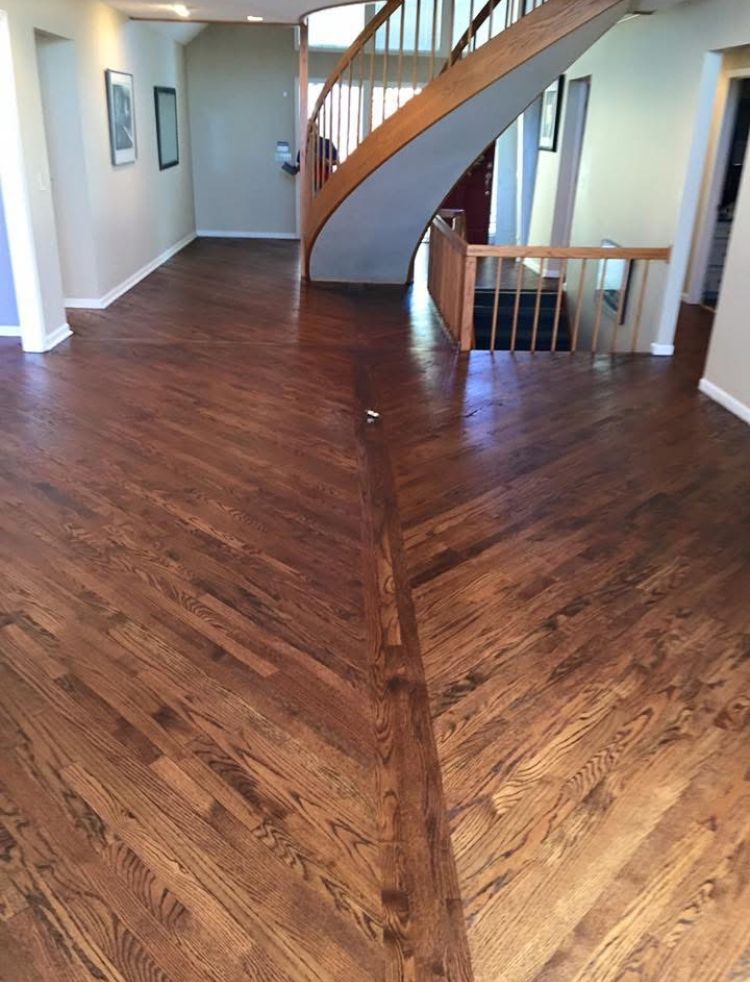 Spacious room with dark wood floors and a curved staircase, viewed from an open entryway.