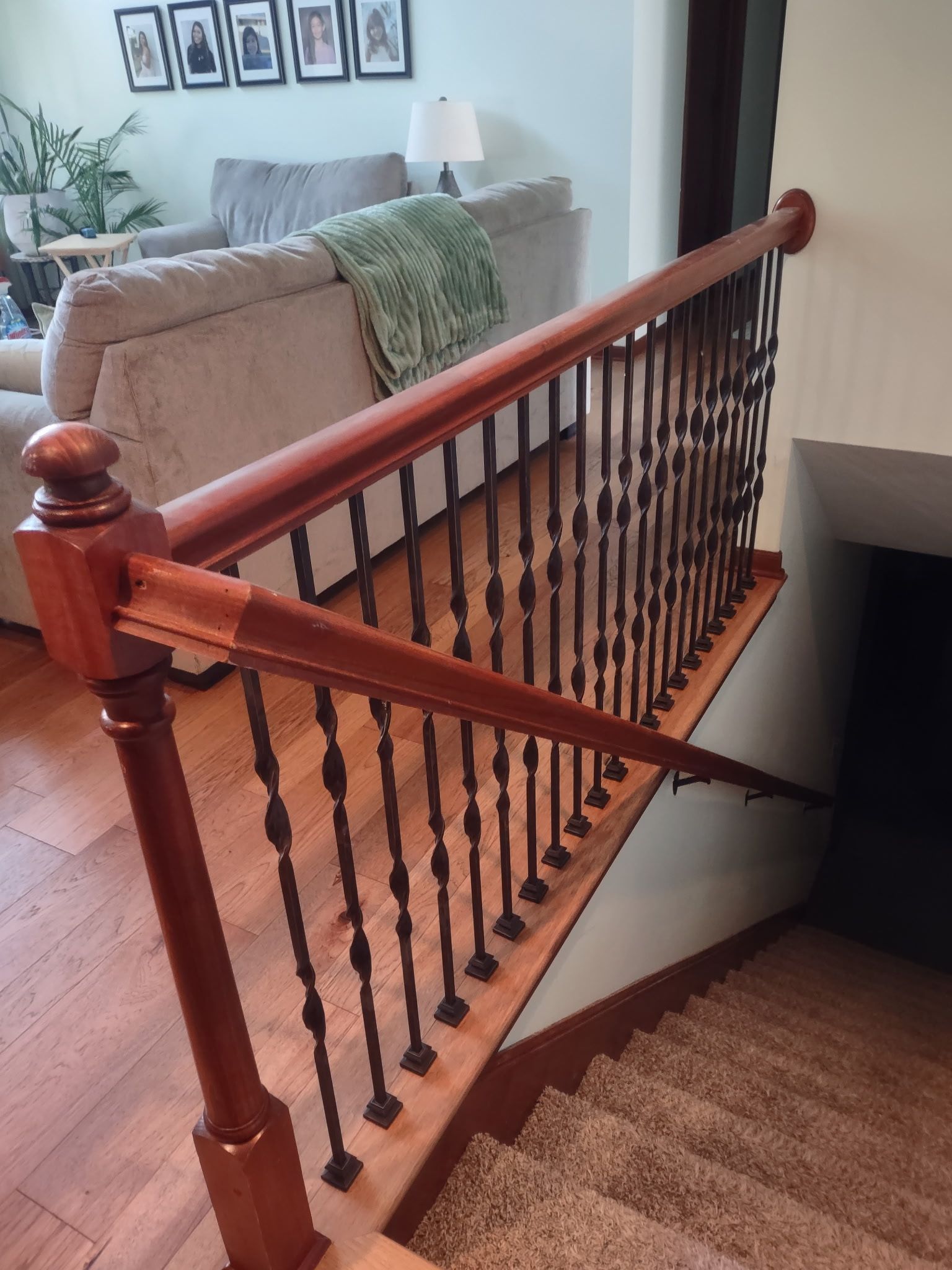 Wooden stair railing with black balusters beside a carpeted staircase in a home interior
