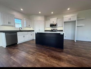 Bright modern kitchen with white cabinets, dark island, and hardwood floors