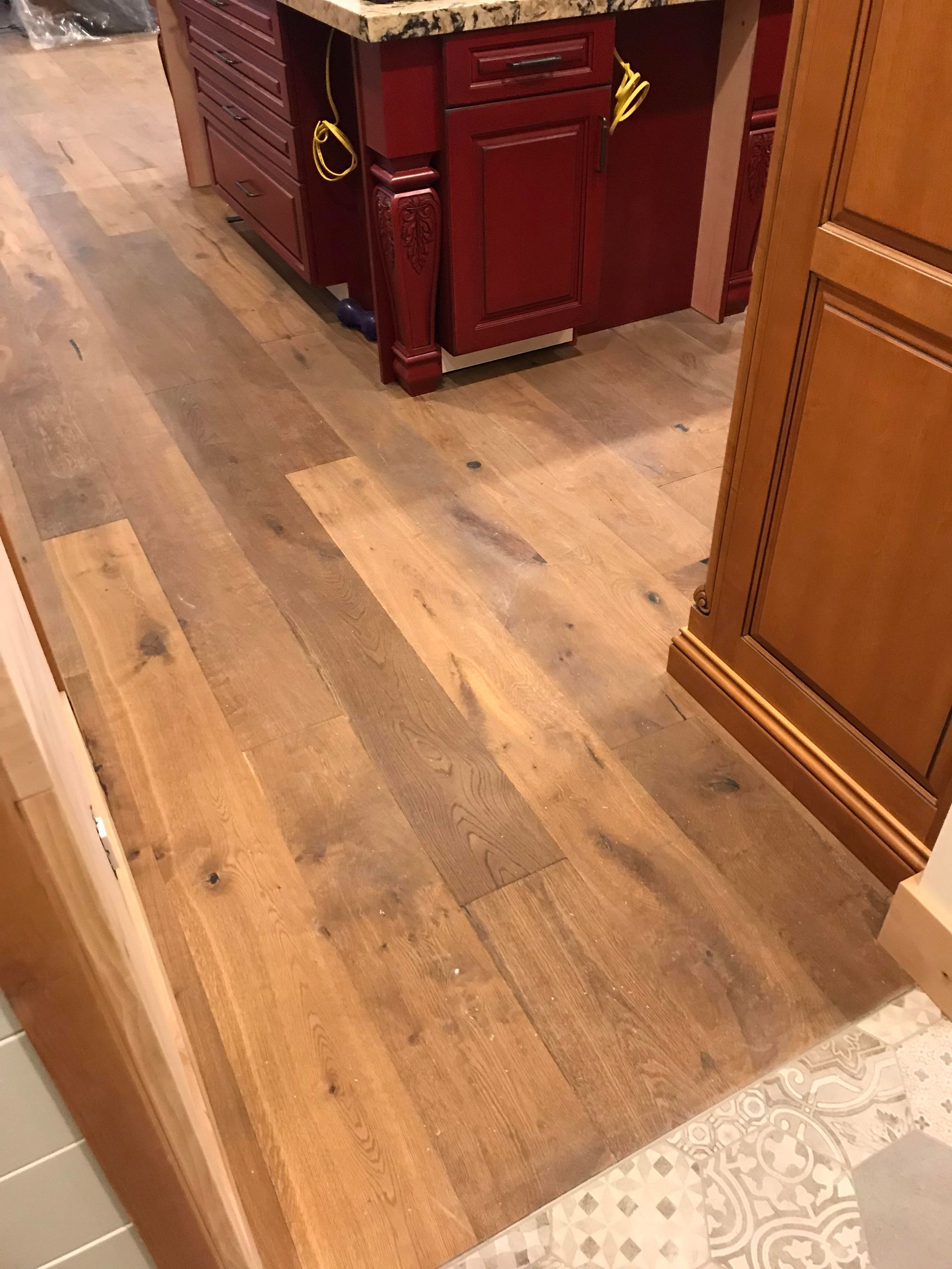Wooden floor in a room with dark red cabinets and wood-paneled walls