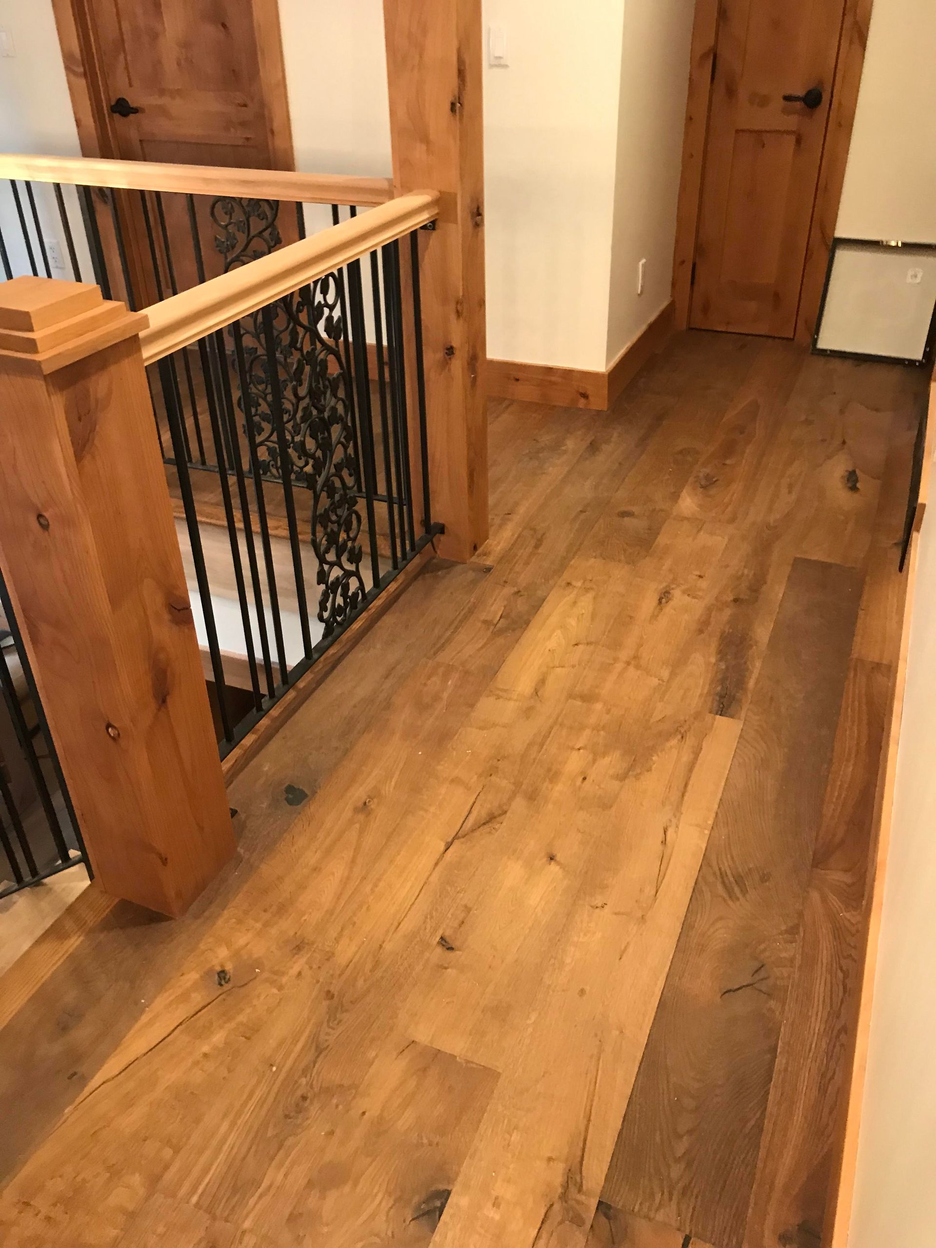 Wooden hallway with banister, exposed beams, and closed doors on the right