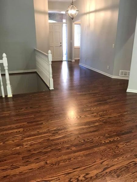Empty hallway with dark wood floors, gray walls, white trim, and a hanging light fixture