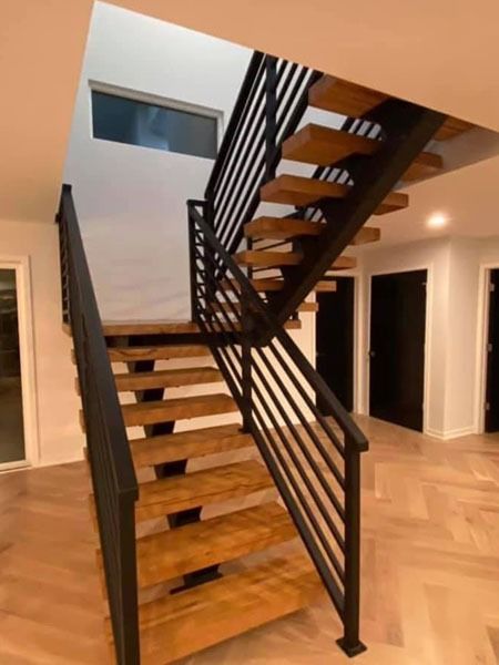 Modern staircase with wooden steps and black metal railings in a bright interior hallway