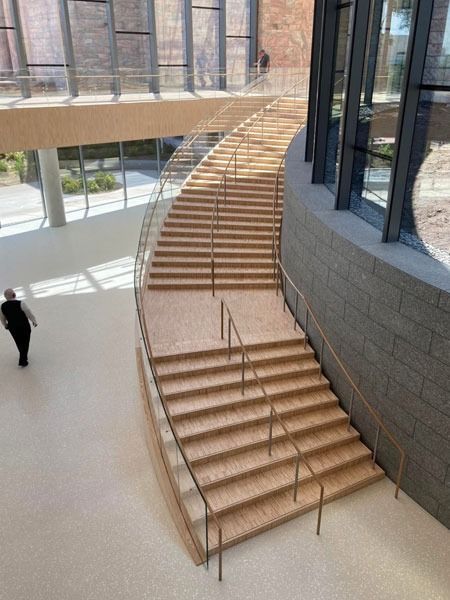 Curved indoor staircase in a modern atrium with a person walking below.