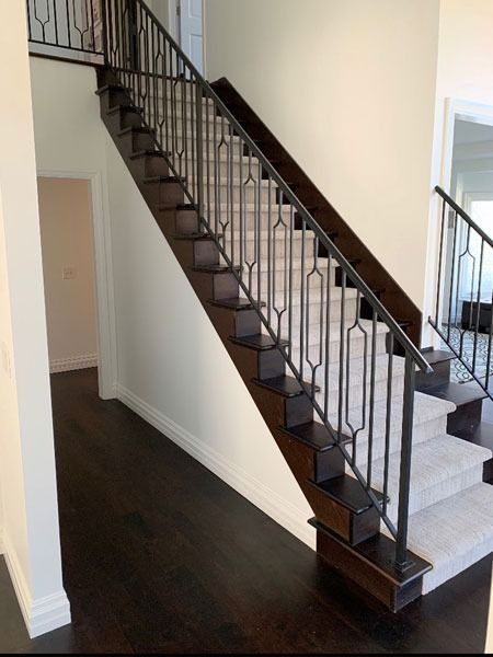 Interior staircase with dark wood steps, black railing, and white walls in a modern home