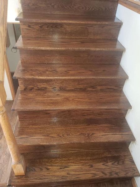 Dark wooden staircase with a simple handrail on the left.