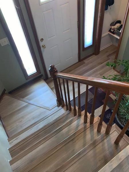 Staircase landing with front door, wooden railings, and narrow windows beside the entryway.
