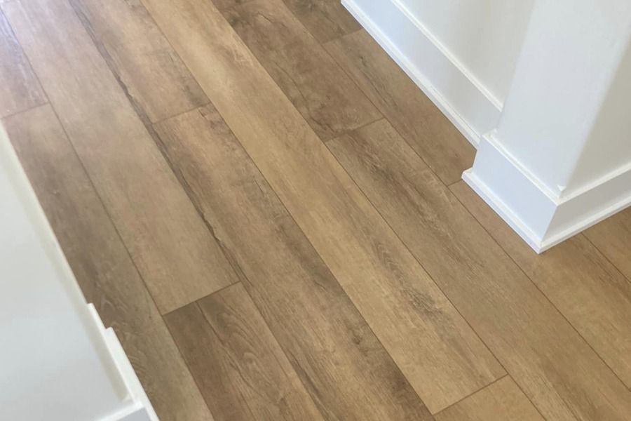 Wood-look plank flooring in a light-colored room corner with white baseboards