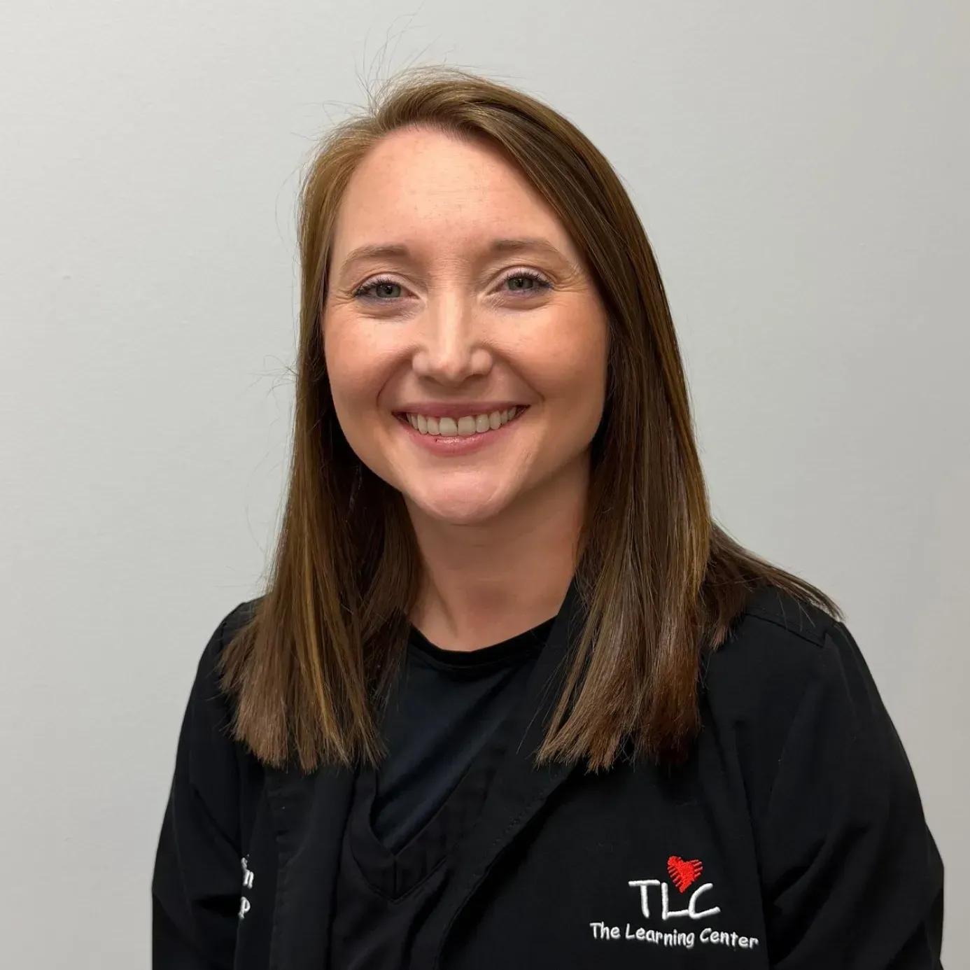 Woman smiling in black jacket, logo 