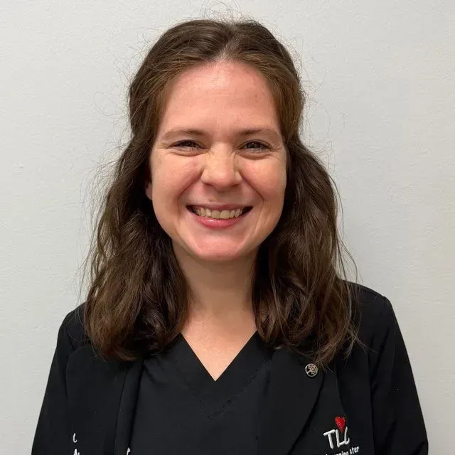Woman smiling, wearing a black top, against a white background.