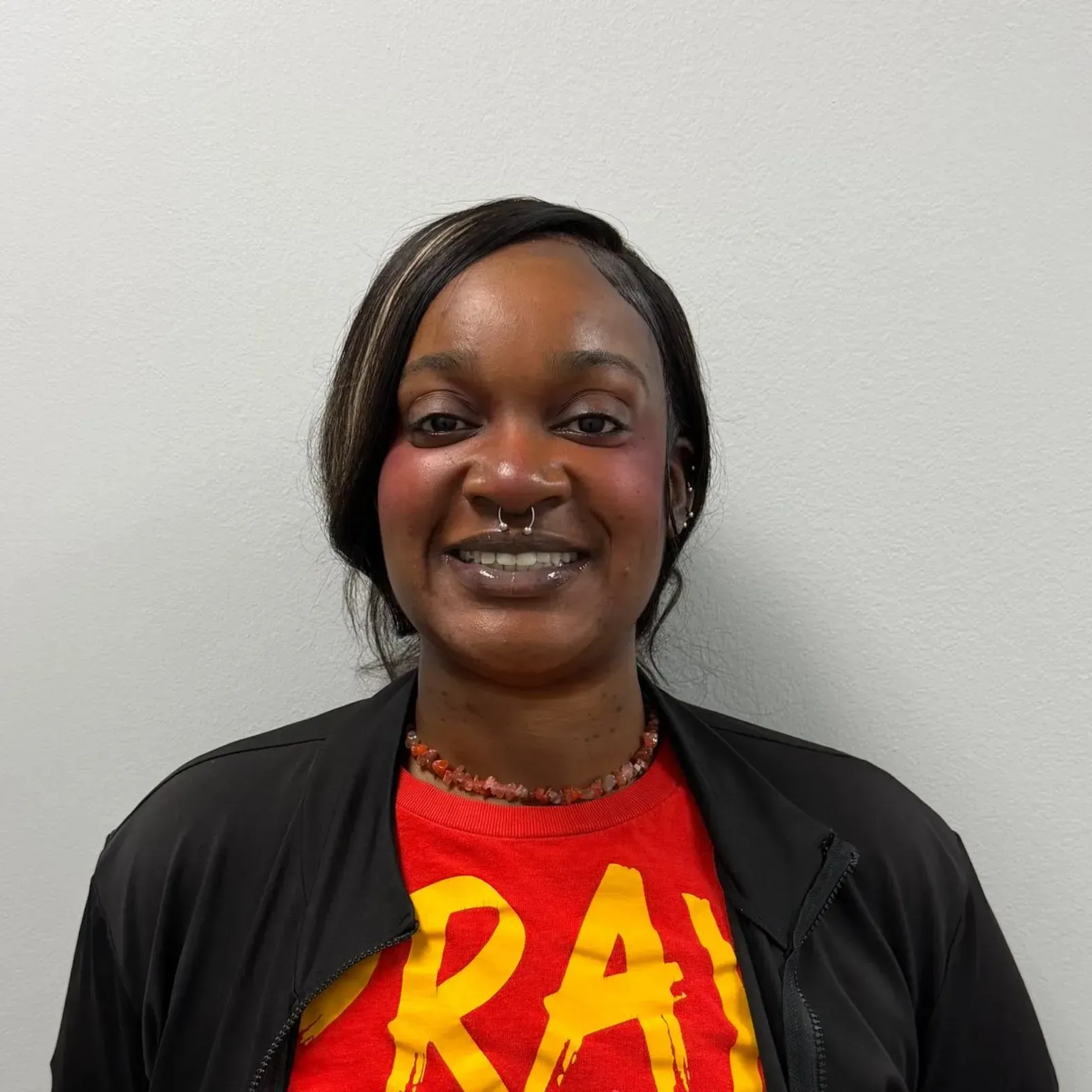 Person wearing a black jacket and a red shirt with the word 