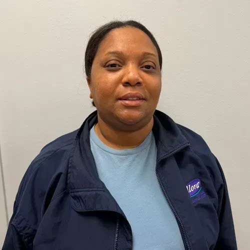 Woman in navy blue jacket and light blue shirt, indoors, looking at camera.
