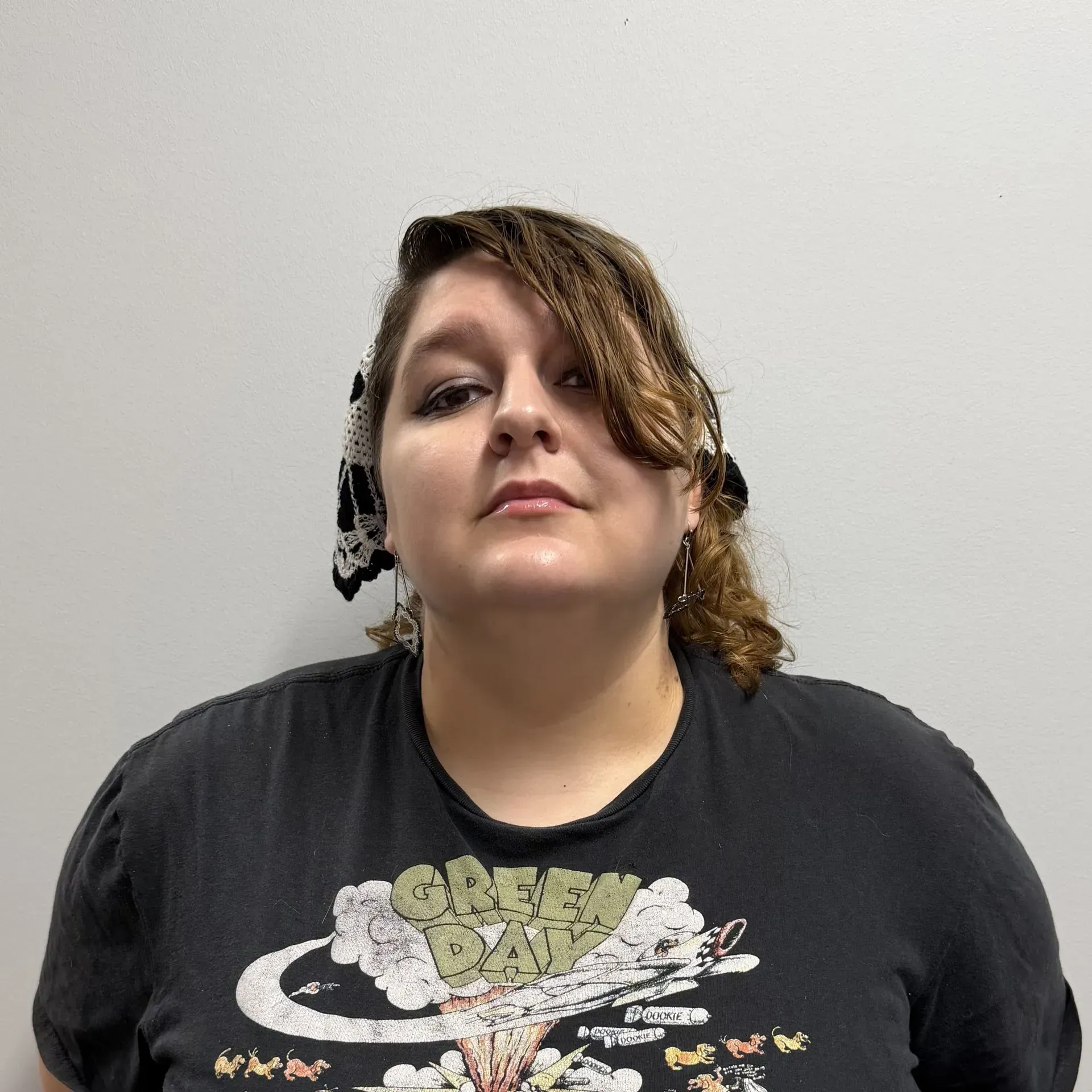 Person wearing a Green Day t-shirt and head scarf, looking up.