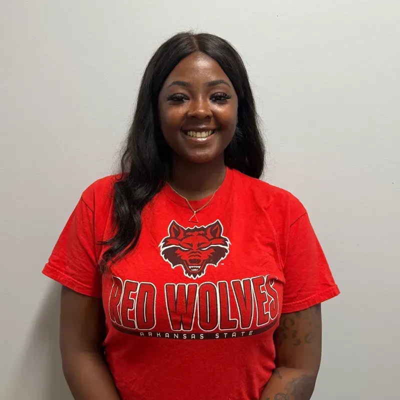 Woman in red shirt with Red Wolves logo smiling.