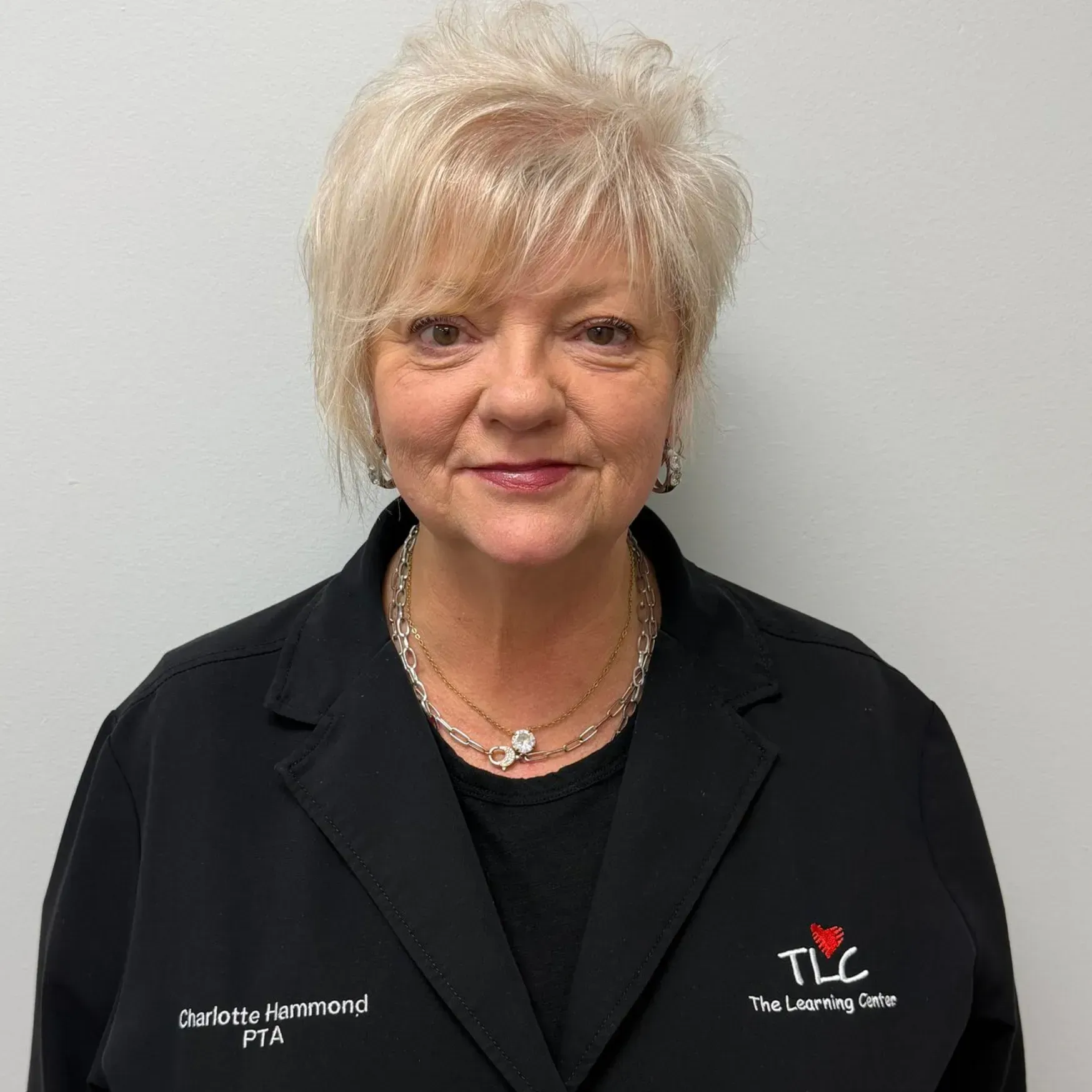 Woman with blonde hair, wearing a black jacket with 